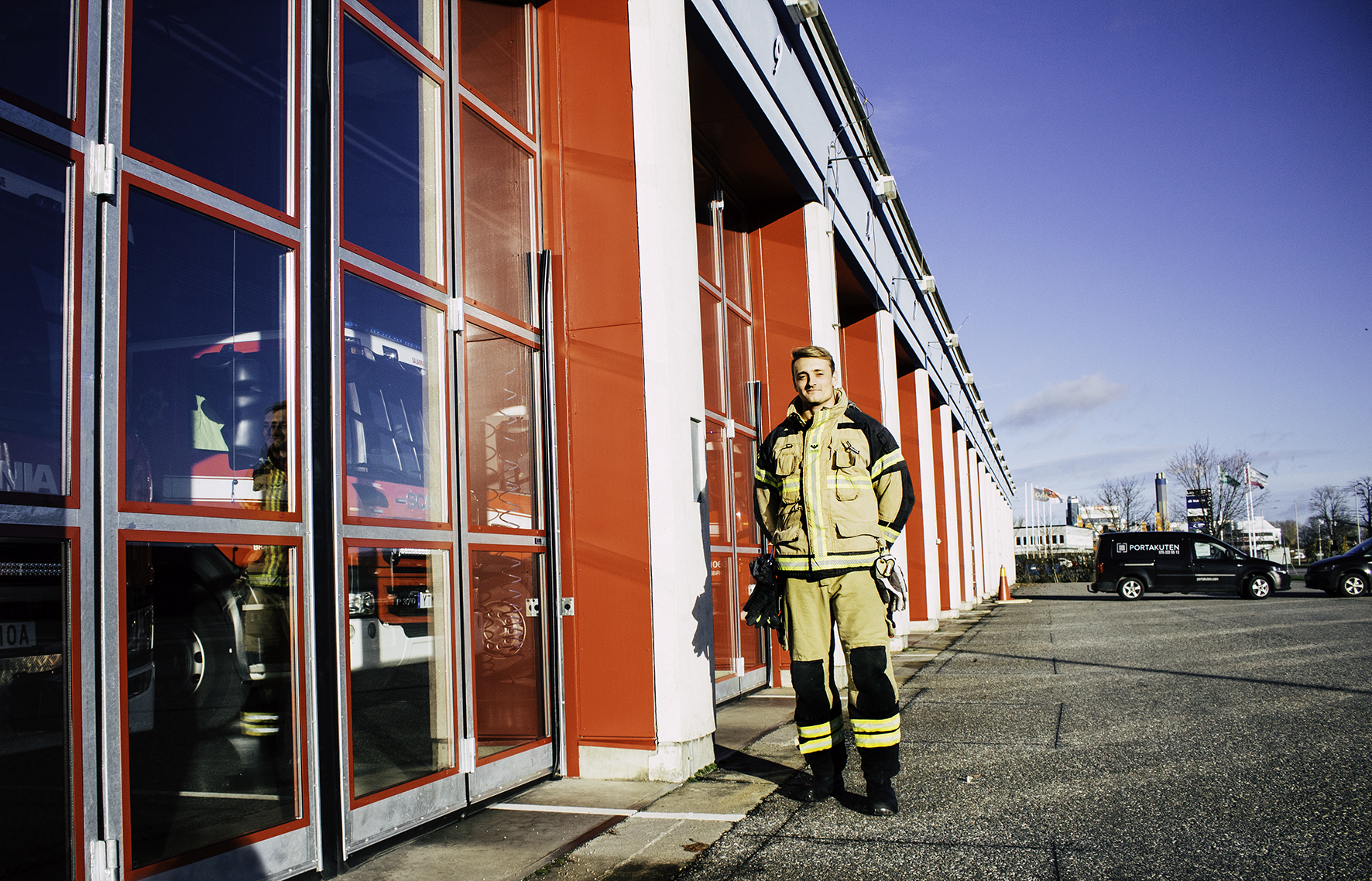Bild tagen utifrån brandstationen. På bild syns en leendes brandman. Bakom honom syns de nya fina portarna.